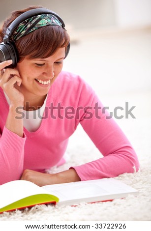 Beautiful female student listening to music and reading