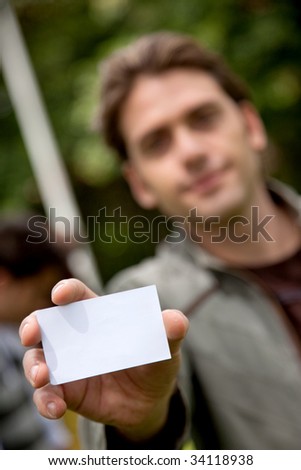 Handsome man displaying his personal card outdoors