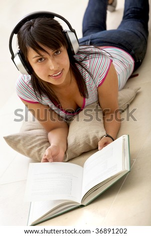 Girl lying on the floor reading and listening to music