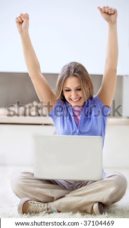 Excited woman with a computer and her arms up