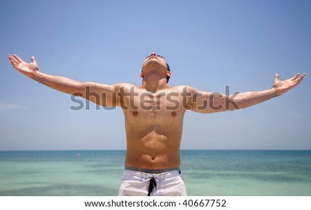 handsome man with arms open having fun at the beach
