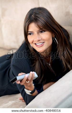 Beautiful woman lying on the couch watching tv at her apartment