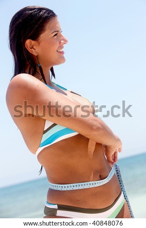 fit female measuring her waist at the beach - weight loss series