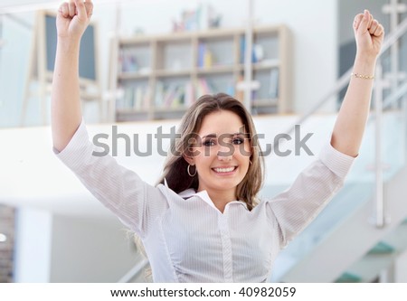 Excited business woman with arms raised at the office