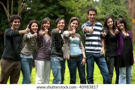 Large group of friends with thumbs up smiling outdoors