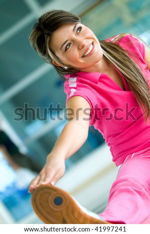 Woman at the gym doing stretching exercises and smiling on the floor