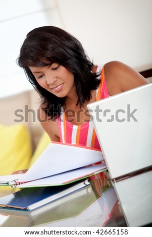 Beautiful girl studying with a laptop and notebooks indoors
