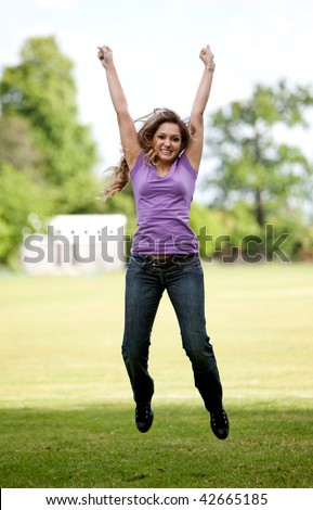 Casual woman exciting and jumping on the park
