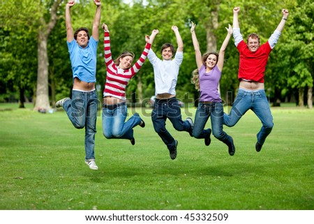 Group of friends jumping outdoors and smiling