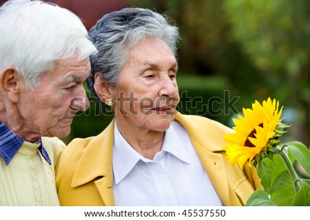 Beautiful couple of elder people looking a sunflower