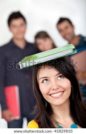 Female student with a book on top isolated over a white background
