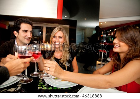 Group of people toasting looking happy at a fancy restaurant
