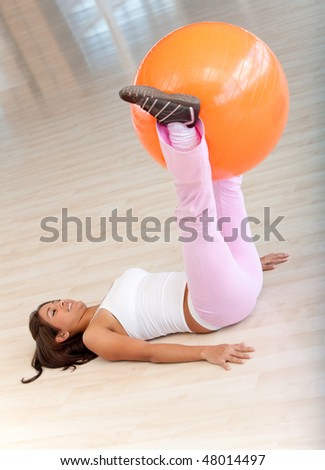 gym woman doing pilates exercises on an orange ball