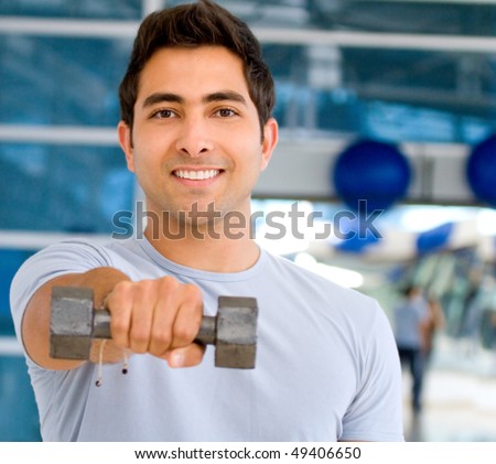 Man at the gym lifting a free-weight and smiling