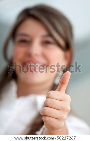 Friendly business woman smiling with thumb up - focus on hand