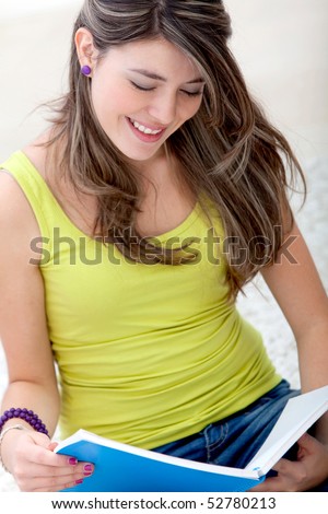 Young woman studying at home with a notebook and smiling