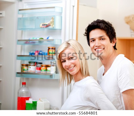 Couple at home looking inside the fridge and smiling