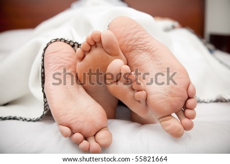 Feet of a couple lying in bed