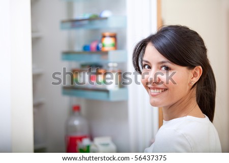 Woman at home looking inside the fridge and smiling