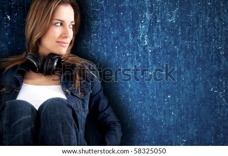 Beautiful woman smiling with headphones and leaning on a blue wall