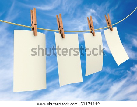 Clothes pin holding white sheets of paper outdoors