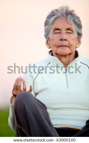 Elder woman doing yoga exercises outdoors - fitness concepts