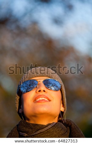 Woman outdoors wearing sunglasses and looking at the sky