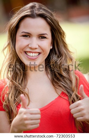 Portrait of a lovely woman with thumbs up outdoors