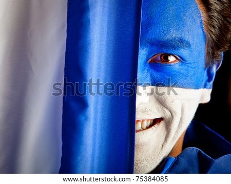 Man with a blue and white flag painted on his face - isolated over black
