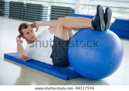 Man at the gym doing exercises for his abs with a Swiss ball