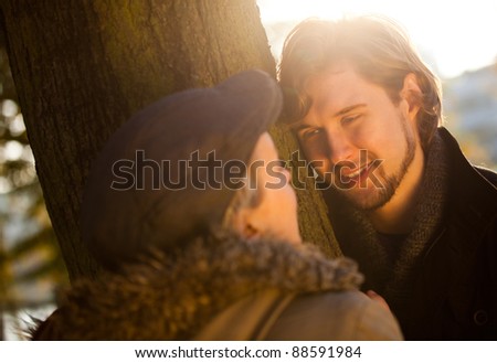 Romantic couple about to kiss behind a tree