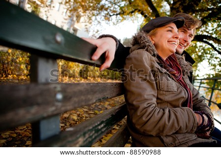 Autumn couple sitting on a bench outdoors