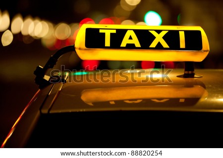 Taxi cab sign on top of the vehicle at nighttime