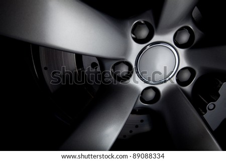 Picture of a black car tire with focus on bolts