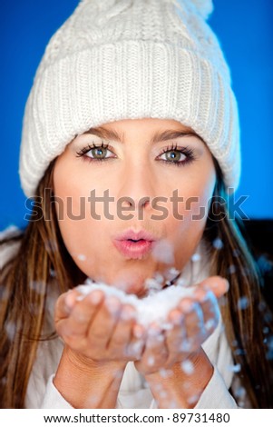 Winter woman blowing snow from her hands