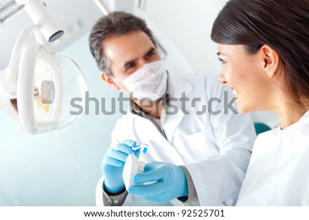 Dentist showing a woman how to brush her teeth on prosthesis