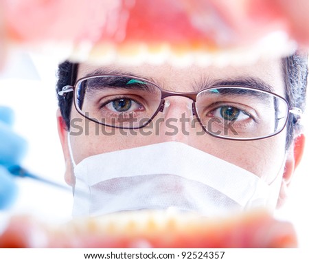 Male dentist working on teeth inside a mouth with an instrument