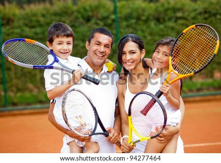 Happy family playing tennis holding rackets at the court