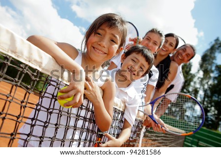 Family of tennis players at the court next to the net