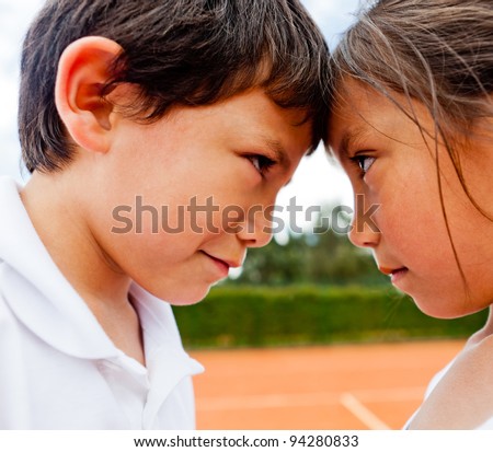 Siblings rivalry - two kids at the tennis court looking competitive