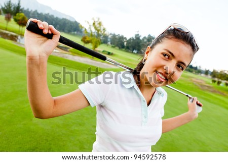 Girl playing golf and holding a golf-club at the field