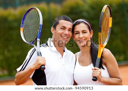 Happy couple of tennis players training outdoors