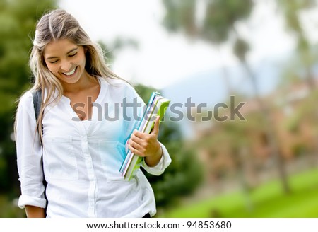 Shy female student walking outdoors and smiling