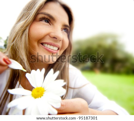 Woman outdoors holding a flower playing he loves me or not