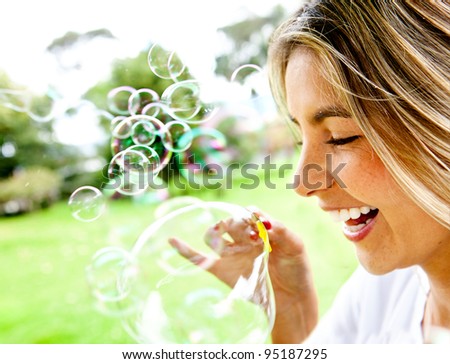 Happy woman portrait blowing soap bubbles at the park