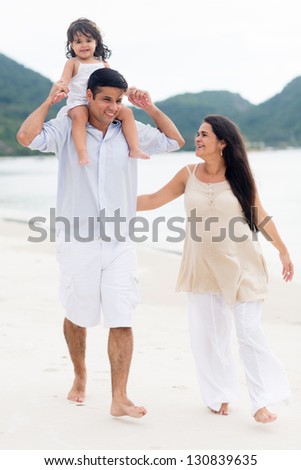 Happy family expecting a new child and walking at the beach