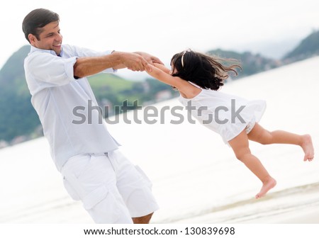 Dad playing with his daughter at the beach looking happy