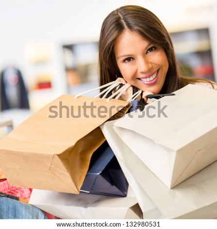 Portrait of beautiful female shopper inside a store holding shopping bags