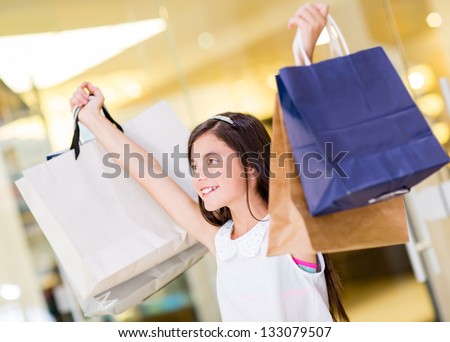 Happy shopping girl holding bags with arms open