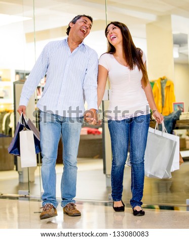 Happy shopping couple holding bags and laughing